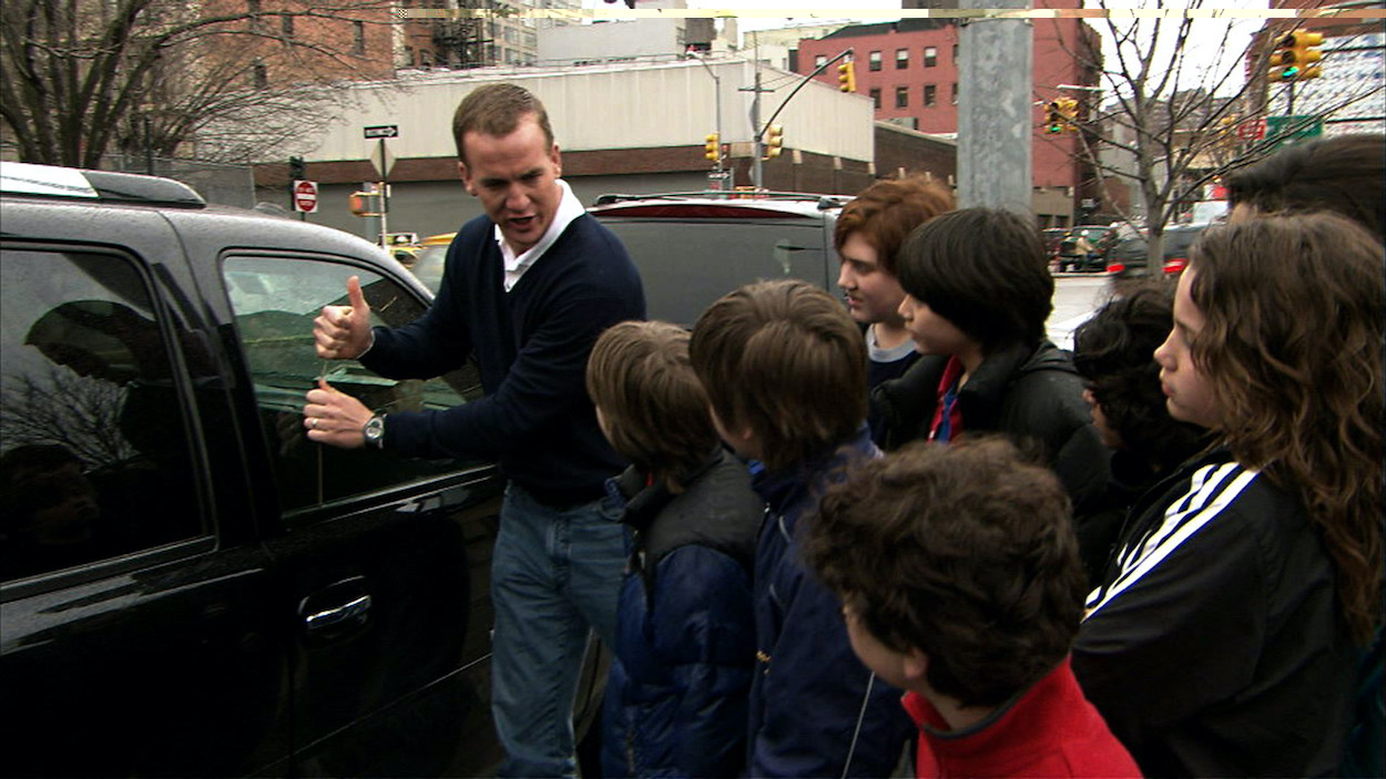 Peyton Manning speaks to children outside of his vehicle | Photo by: Dana Edelson/NBCU Photo Bank