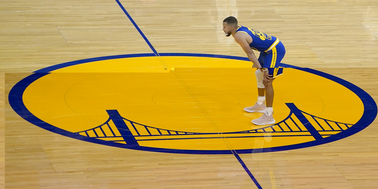 Stephen Curry stands on the Golden State Warriors logo in April 2021